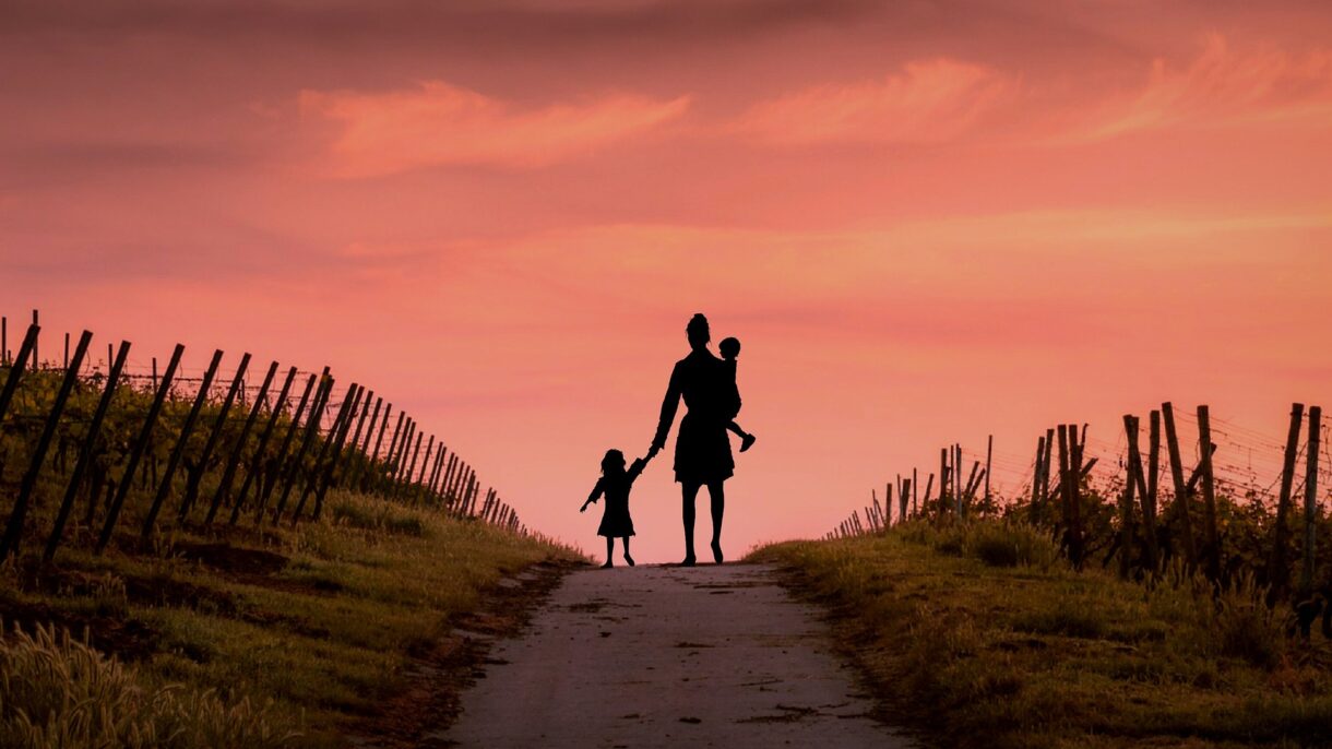 Familie spaziert bei Sonnenuntergang auf Weinbergweg.