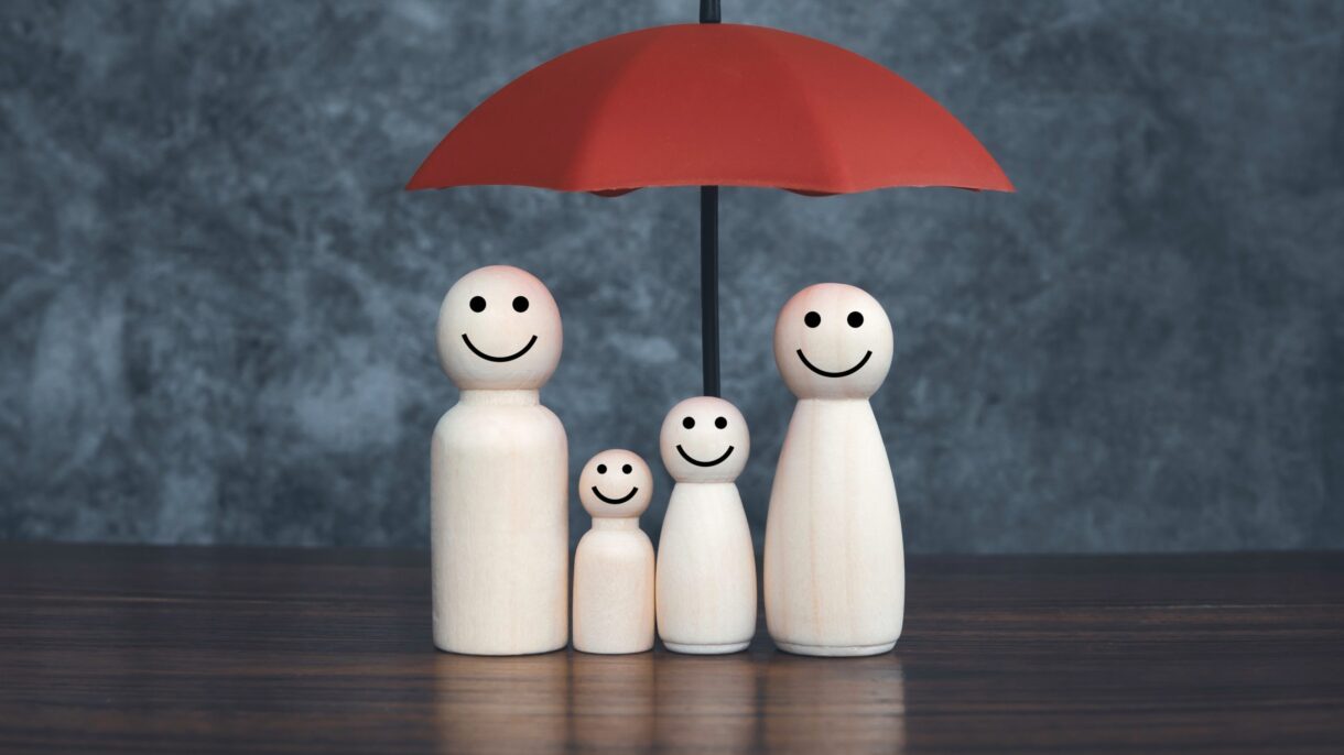 Holzfigurenfamilie unter rotem Regenschirm