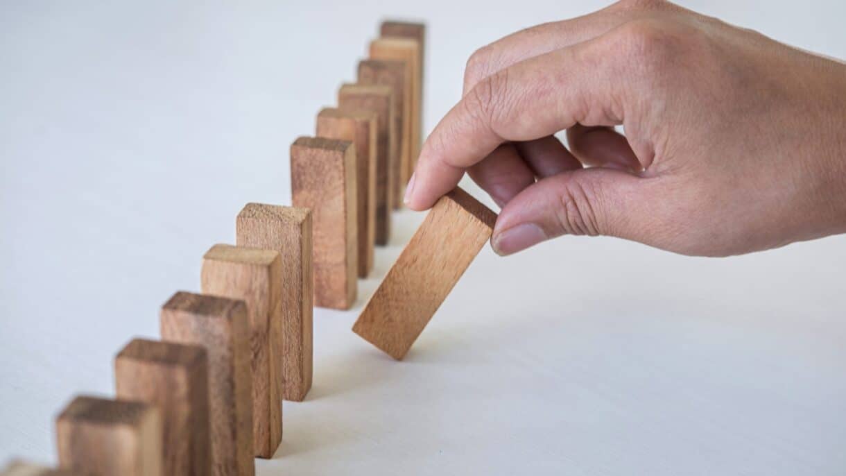 Hand stoppt fallende Dominosteine